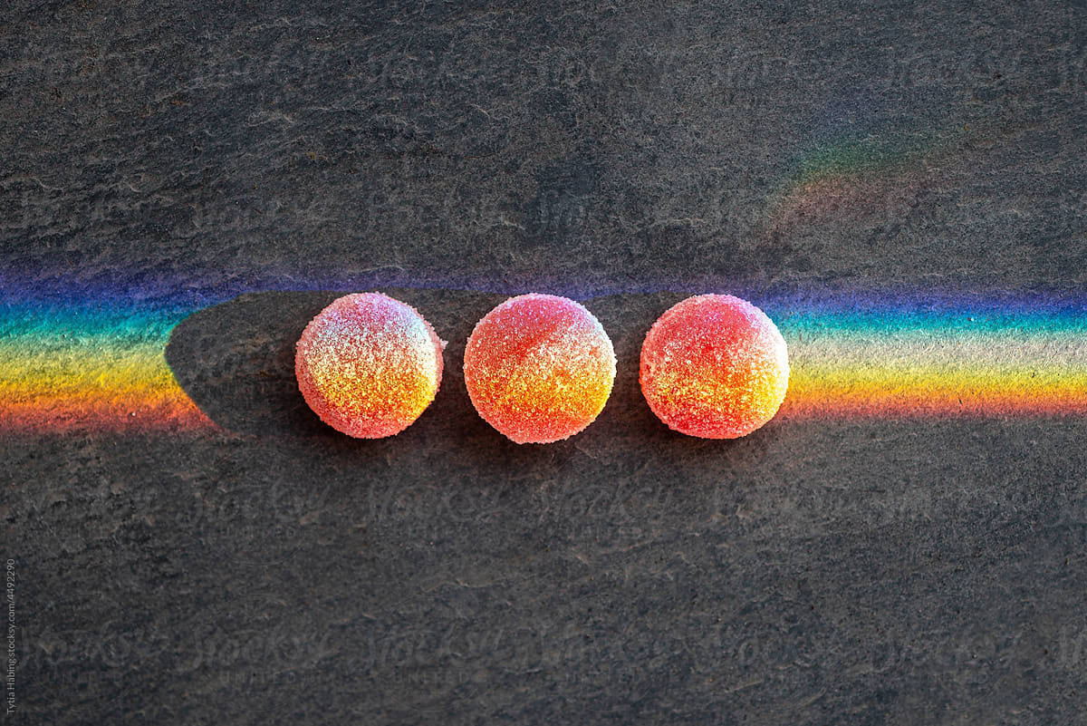 three cannabis red gummy edibles on a black background.